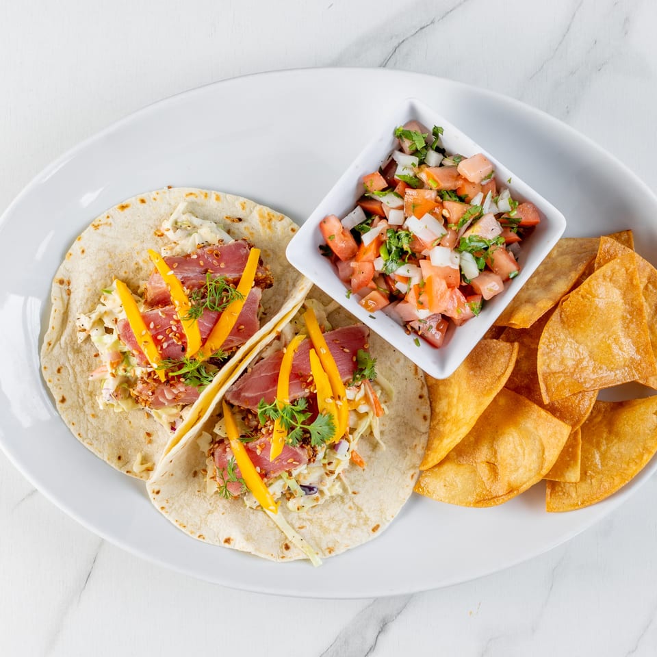 Plate of tuna tacos with mango, slaw, pico de gallo, and crispy tortilla chips.